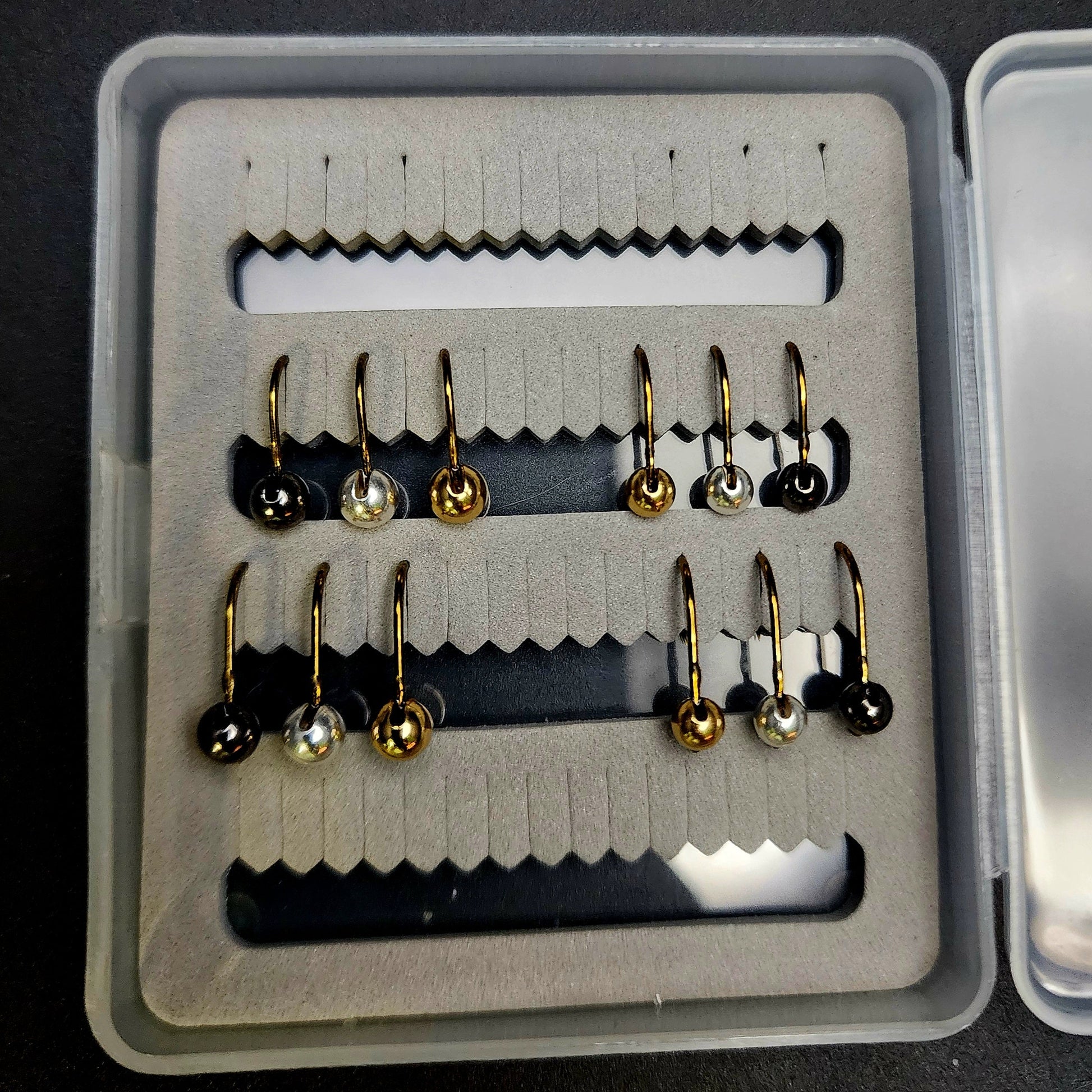 Set of fishing hooks in a box on a black background