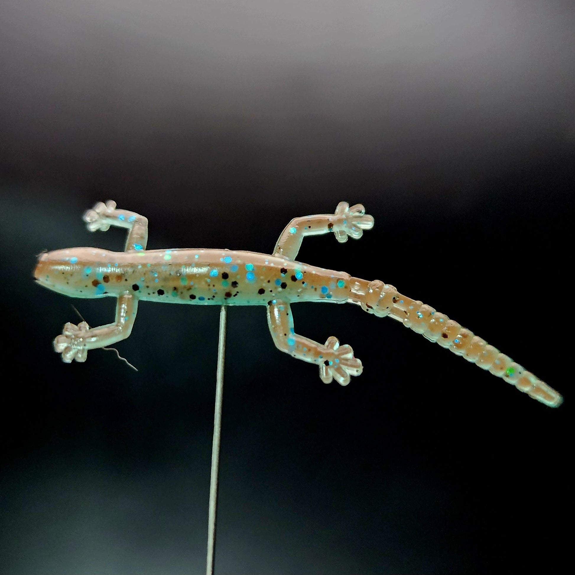 Glowing lizard-shaped lure on a black background