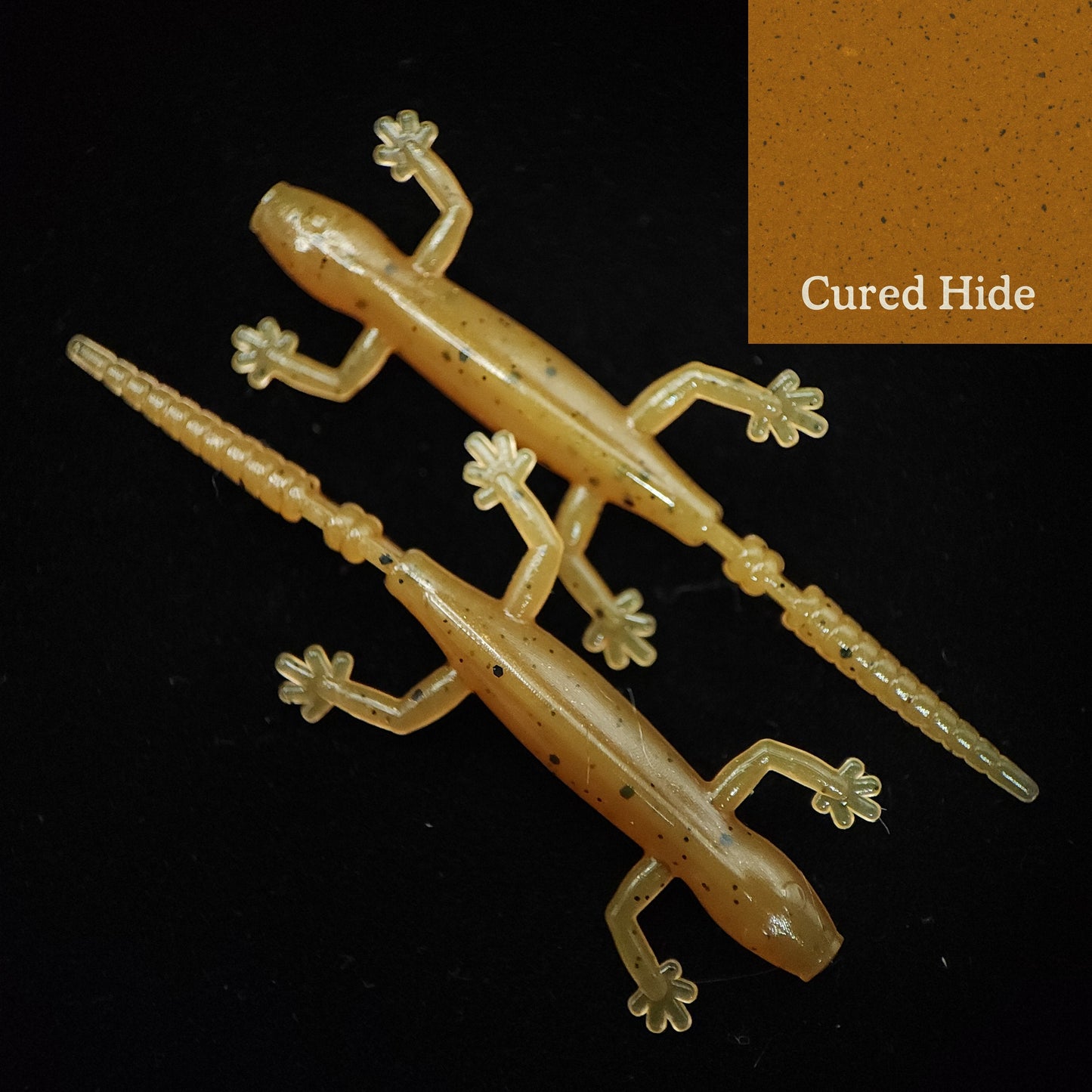 Two lizard-shaped fishing lures on a black background with 'Cured Hide' text.