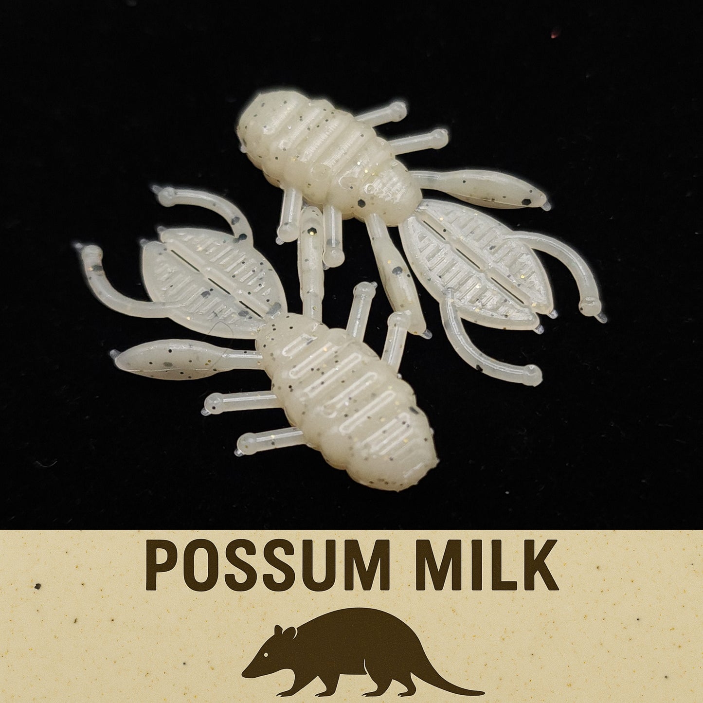 Two white crawfish-shaped fishing lures on a black background with 'Possum Milk' text and possum illustration.