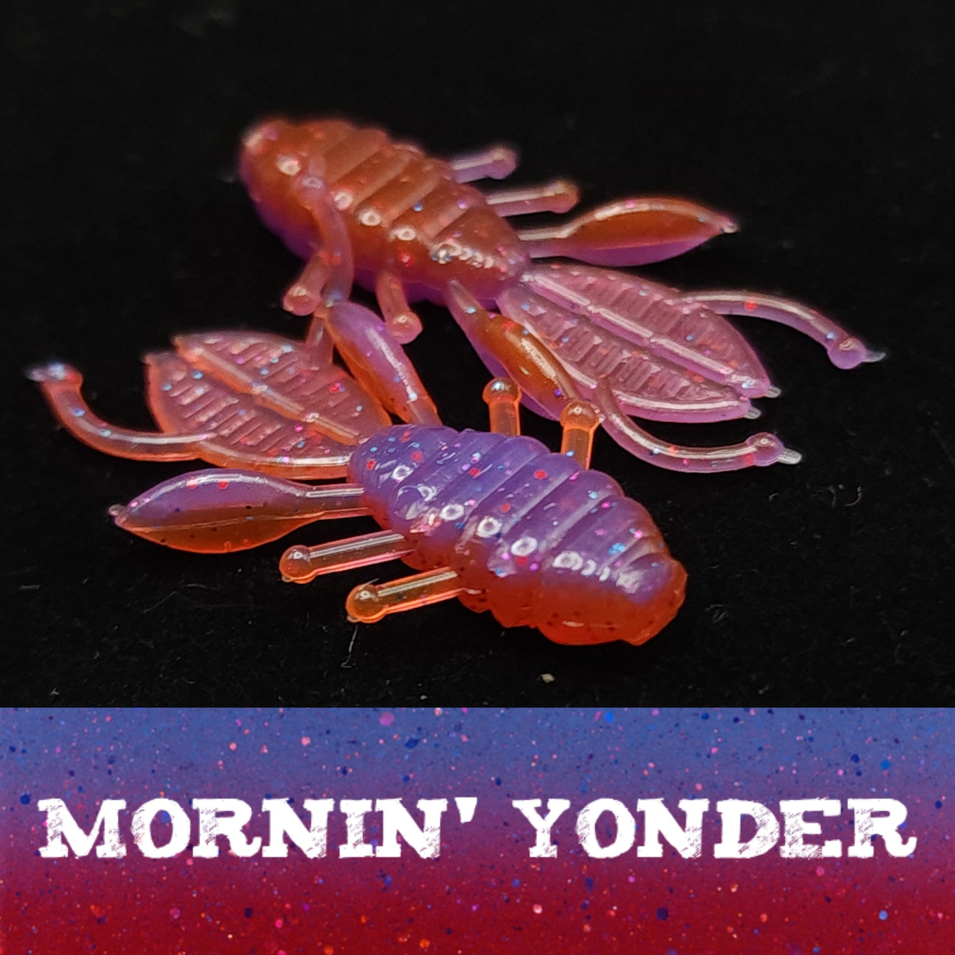 Pink and purple crawfish-shaped fishing lure with 'Mornin' Yonder' text on a dark background