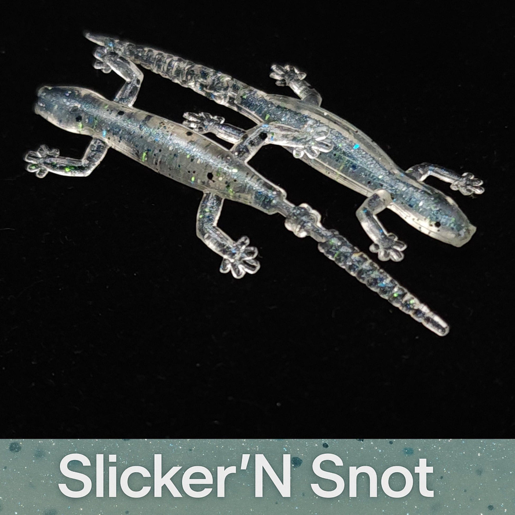 Two glittery lizard-shaped objects on a black background with 'Slicker'N Snot' branding.